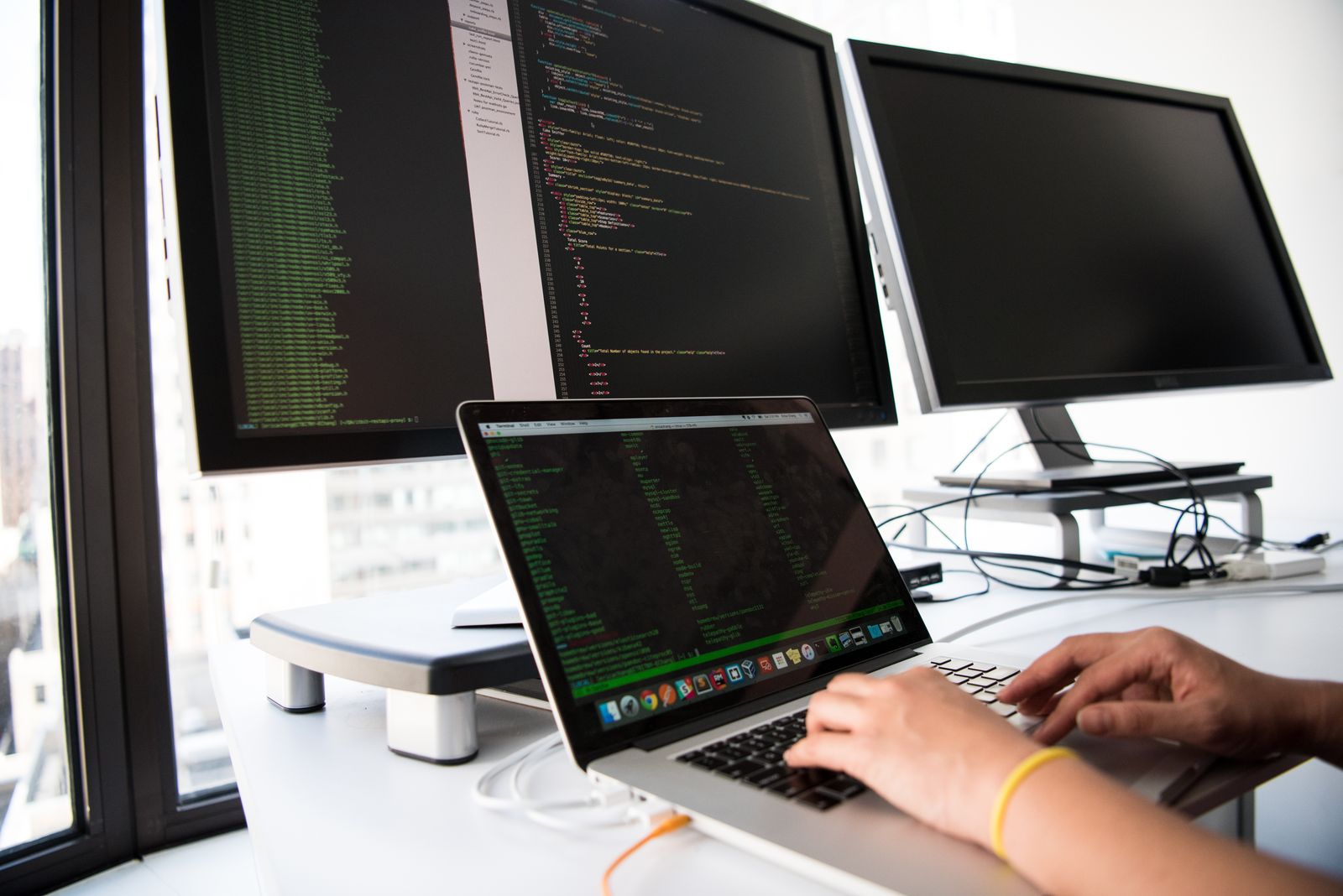 Werkplek met meerdere schermen vol code
