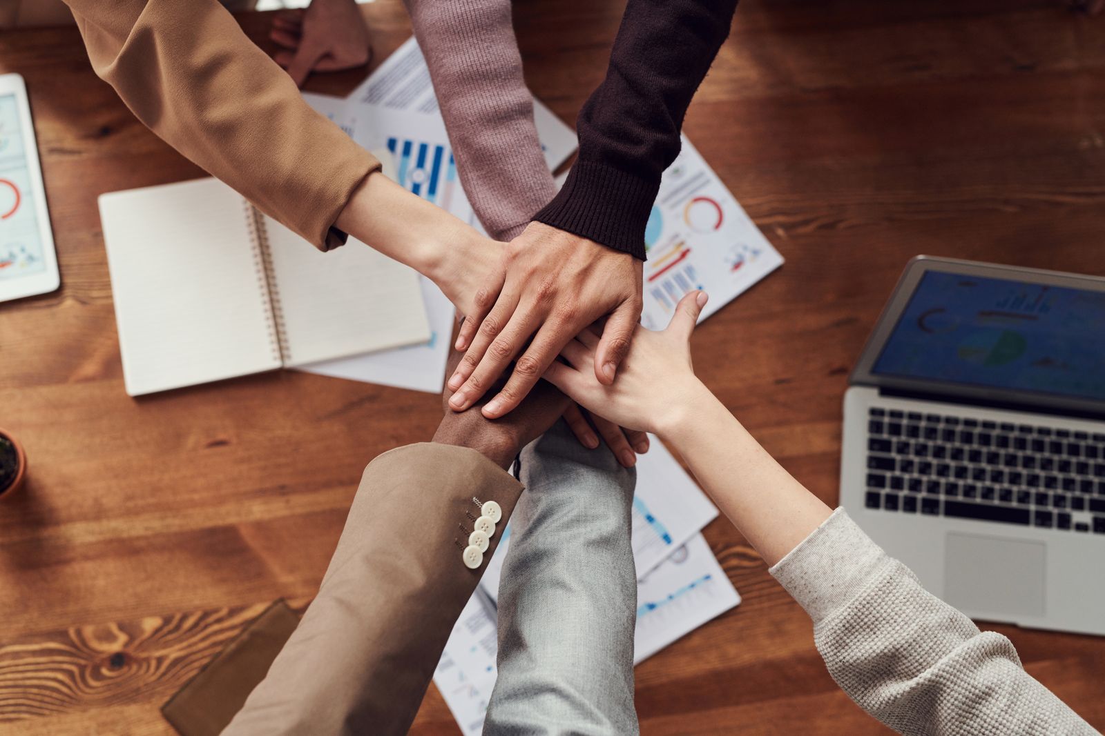 Handen van een team op elkaar boven een werktafel